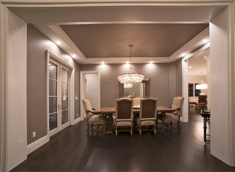 Dining room with a 6 seater dining set and a tray ceiling adorned with a warm chandelier.