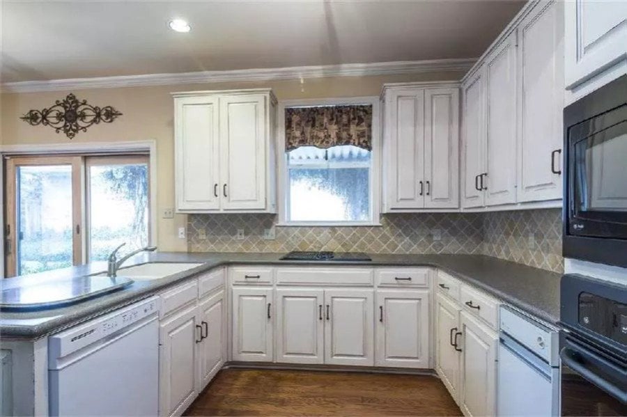 Kitchen with white cabinets, contrasting countertops, and a peninsula bar.