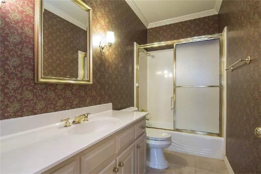 Bathroom with adorned with chrome accents and a vintage wallpaper.