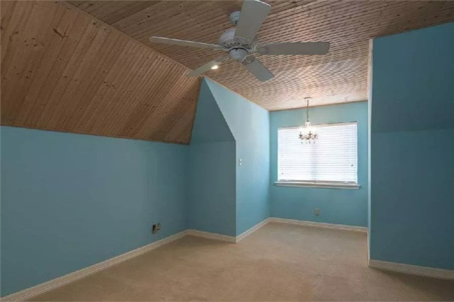 Bedroom with blue walls and a vaulted ceiling clad in wood planks.