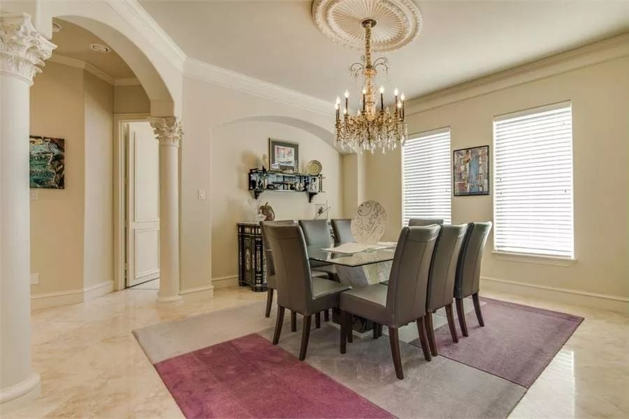 Dining room with a buffet table and an 8-seater dining set illuminated by a brass chandelier.