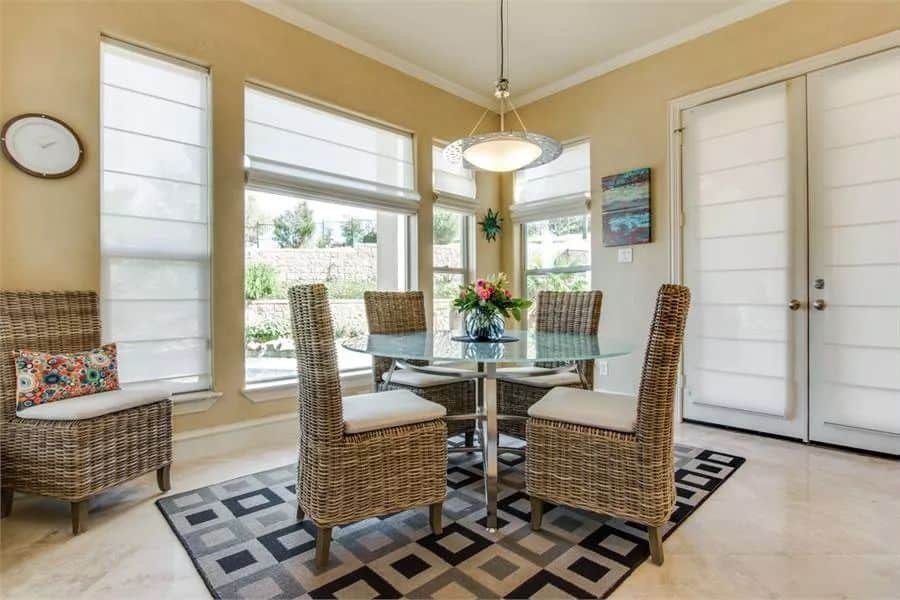 Breakfast nook with a glass-top dining table surrounded by wicker chairs.
