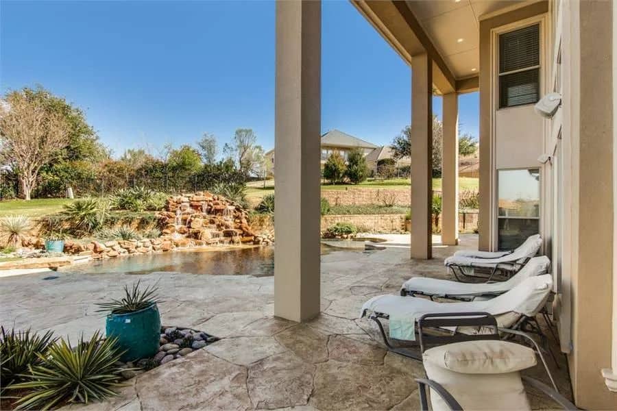 Covered veranda with metal loungers over flagstone flooring.