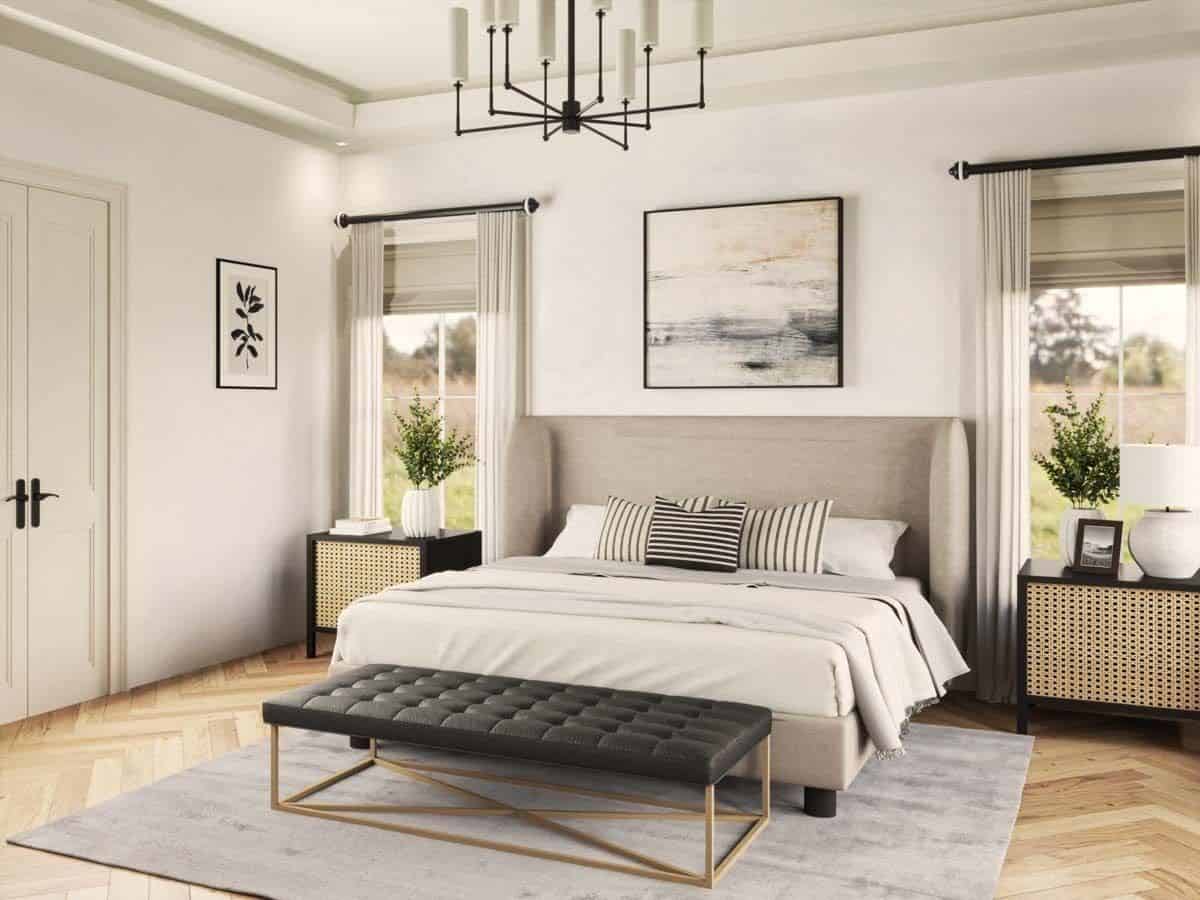 A tray ceiling adorned with a wrought iron chandelier adorns the primary bedroom.