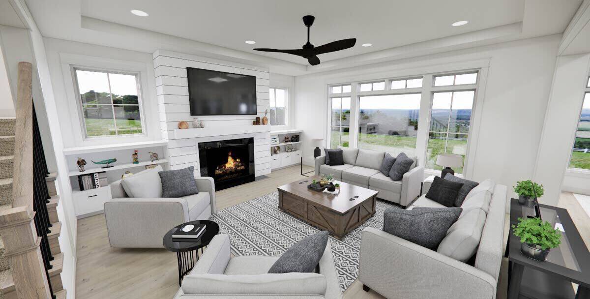 Great room with a tray ceiling, gray seats, and a fireplace topped with a TV.