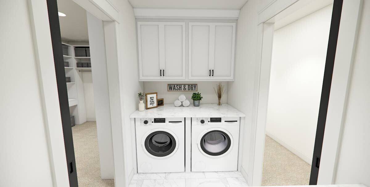 Laundry room with white cabinets and front-load appliances under a marble countertop.
