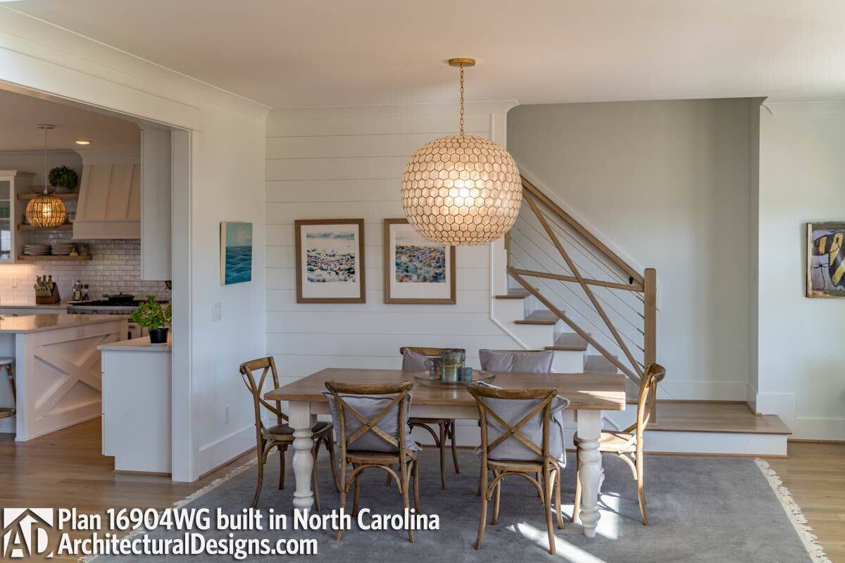 Dining room with cushioned chairs and a wooden dining table illuminated by an oversized pendant.