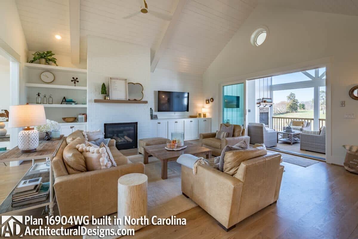 Great room with brown sofas, a wall-mounted TV. and a brick fireplace.