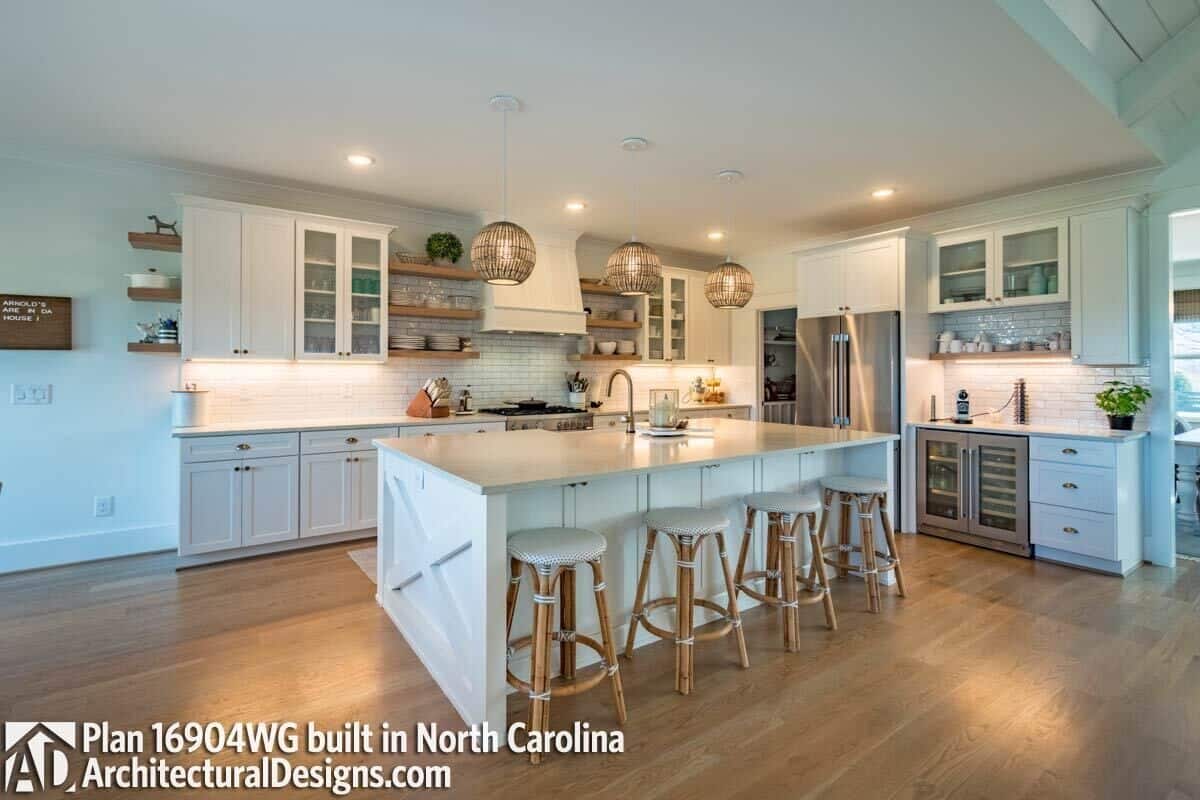 Kitchen with white cabinetry, modern appliances, and a breakfast island lined with round bar stools.