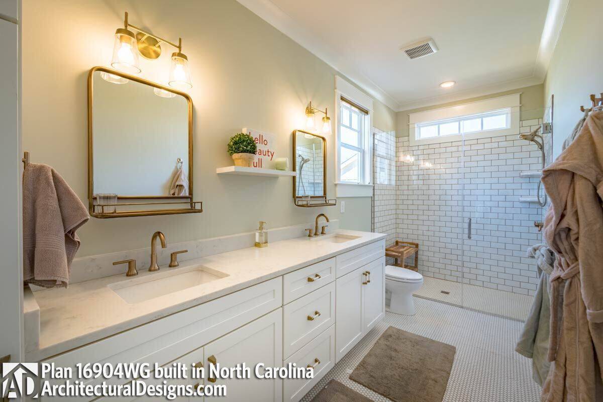 Primary bathroom with a dual sink vanity, a toilet, and a walk-in shower.