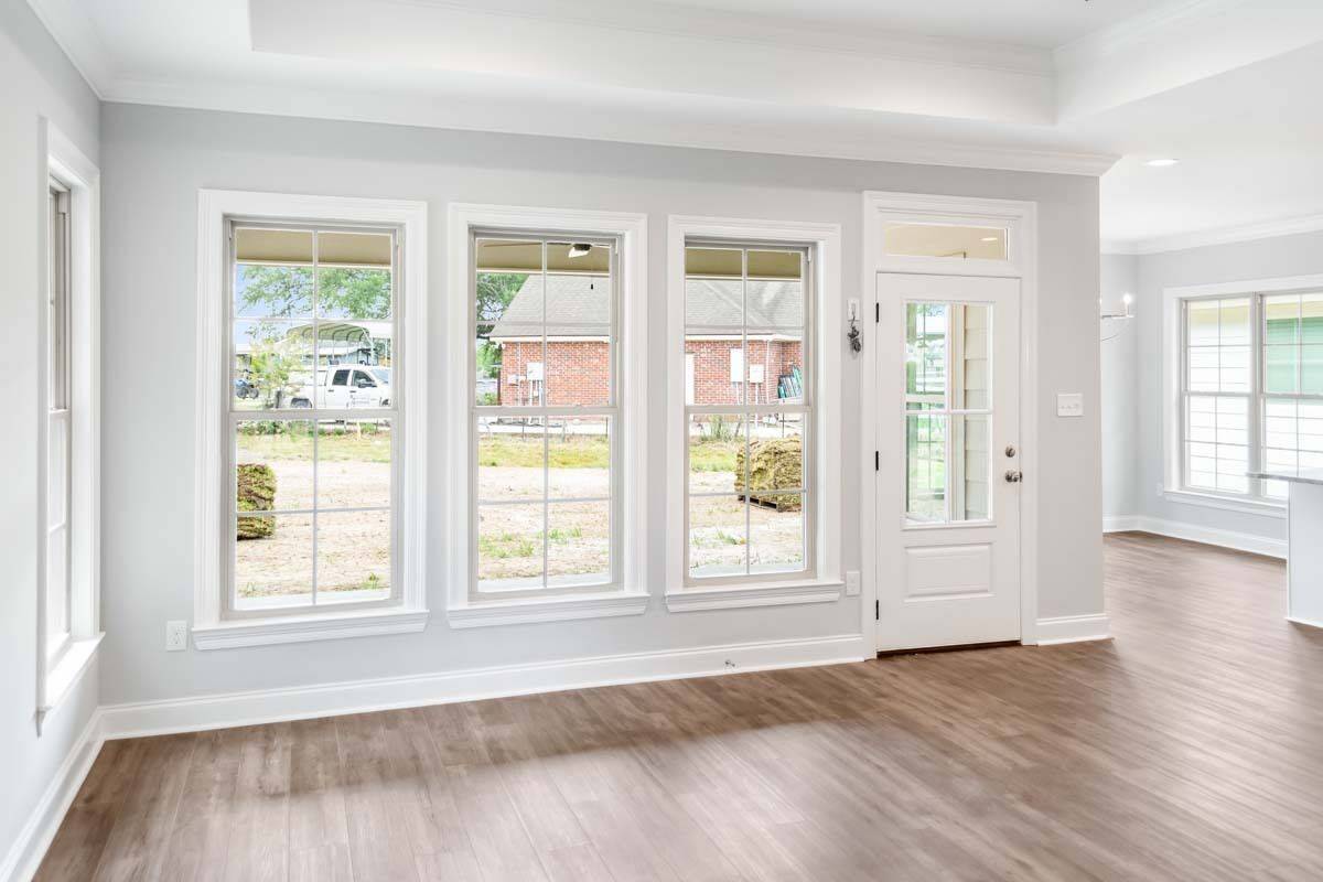 Living room with plenty of windows, a tray ceiling, and a glazed door that opens to a covered porch.