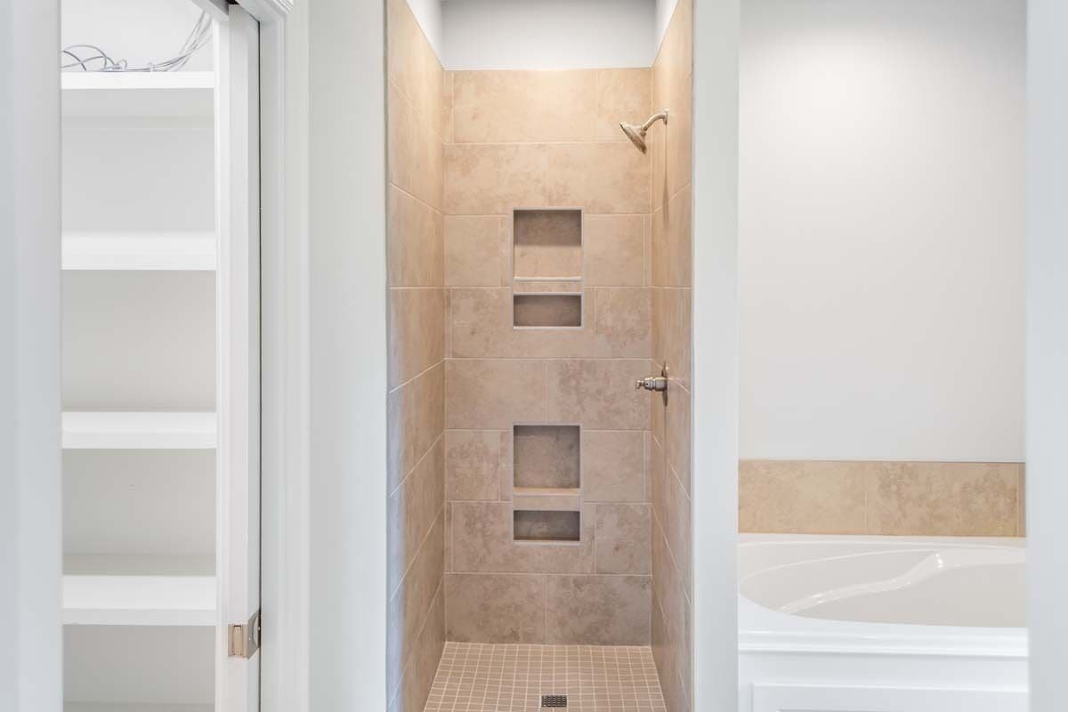 The primary bathroom includes a tiled shower with inset shelves and chrome fixtures.