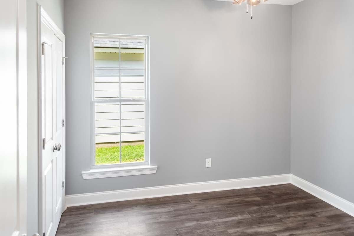 Secondary bedroom with a hardwood floor and gray walls lined with base moldings.
