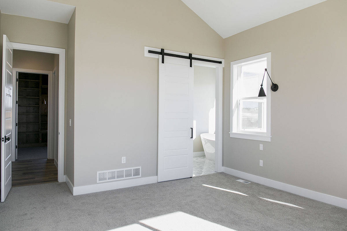 Primary bedroom with a vaulted ceiling and an ensuite bath with a sliding barn door.
