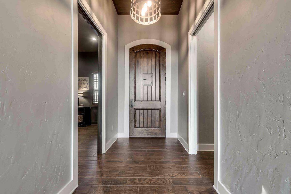 Foyer with an arched wood door and a matching hardwood flooring.