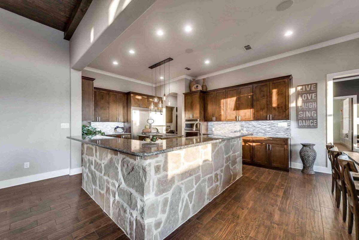 Kitchen with a stone island and wooden cabinets that blend in with the hardwood floor.