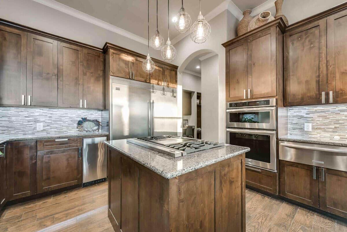 The kitchen includes a cooktop island, stainless steel appliances, and a walk-in pantry.