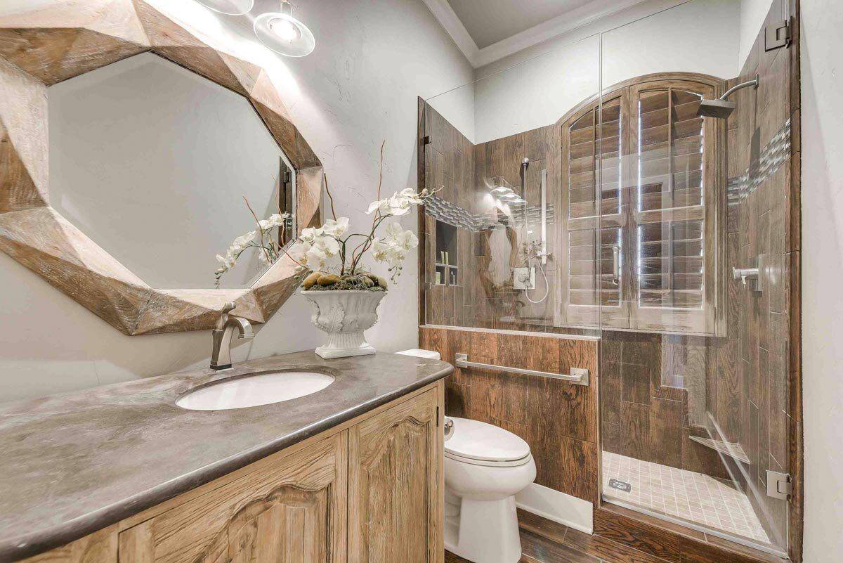 Bathroom with a walk-in shower and a wooden vanity paired with a decorative mirror.
