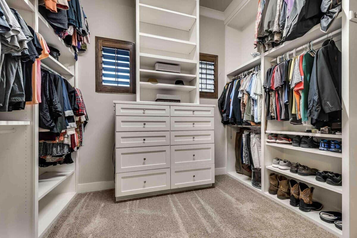 Primary walk-in closet with ample storage and louvered windows.