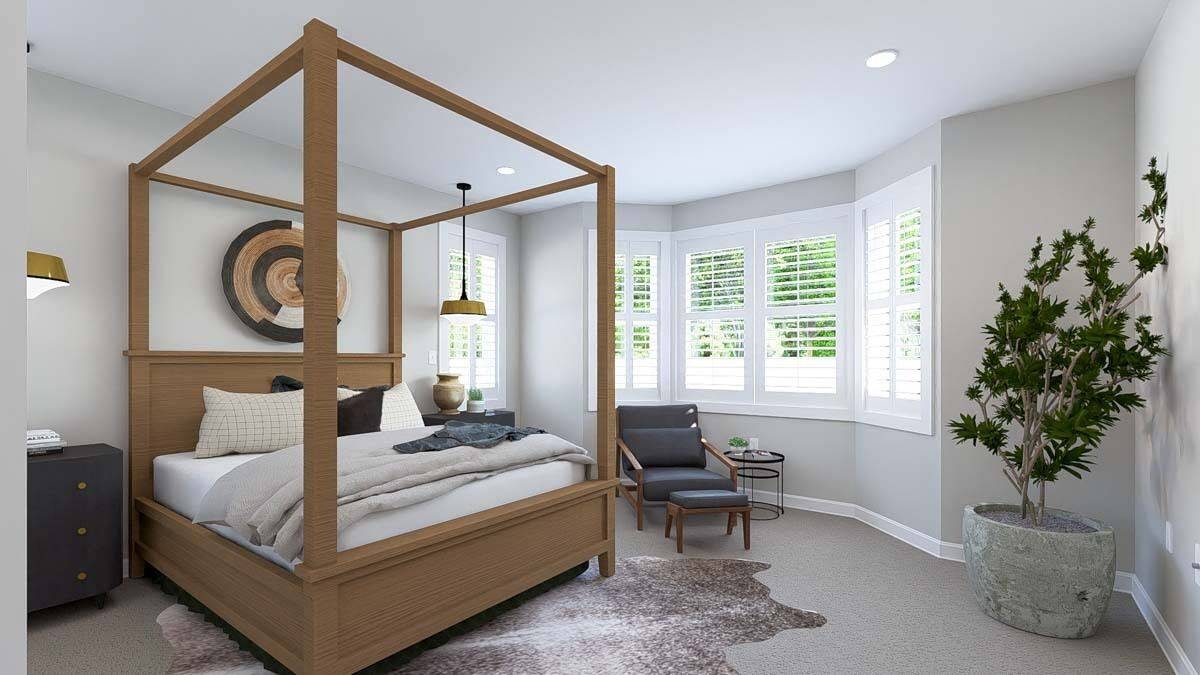 Primary bedroom with a canopy bed and a sitting area by the bay window.