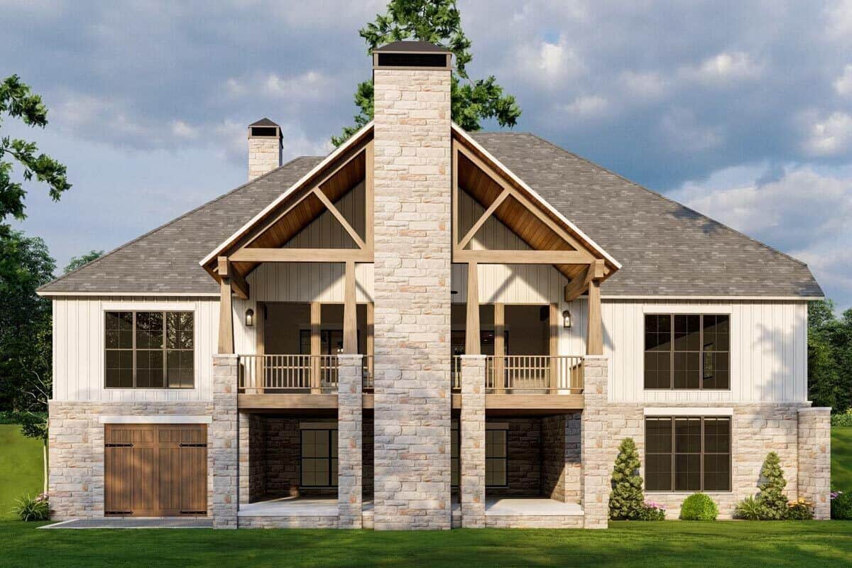 Rear view of the house showcasing a gabled porch, a stone chimney, and a walkout basement.