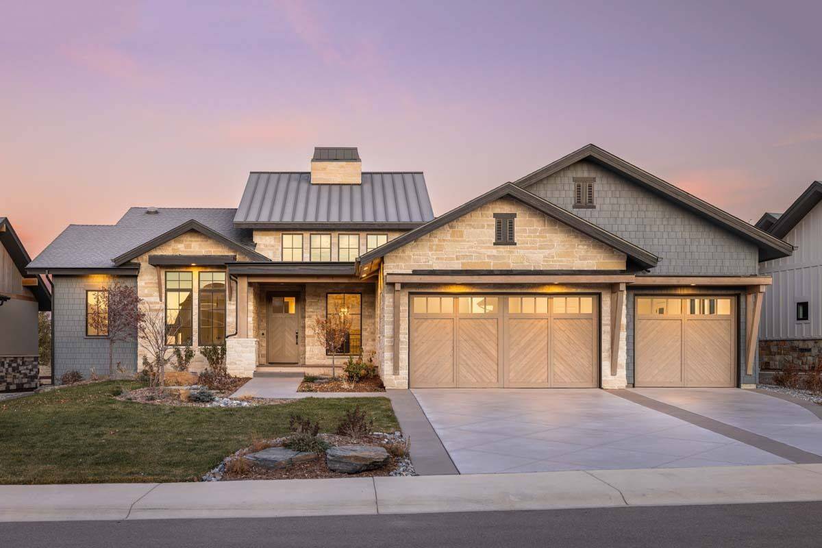 Front view of the house with a covered entry porch and a 3-car garage with large wooden doors.