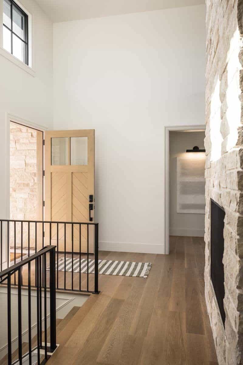 Foyer with a glazed front door and a striped runner over the hardwood flooring.