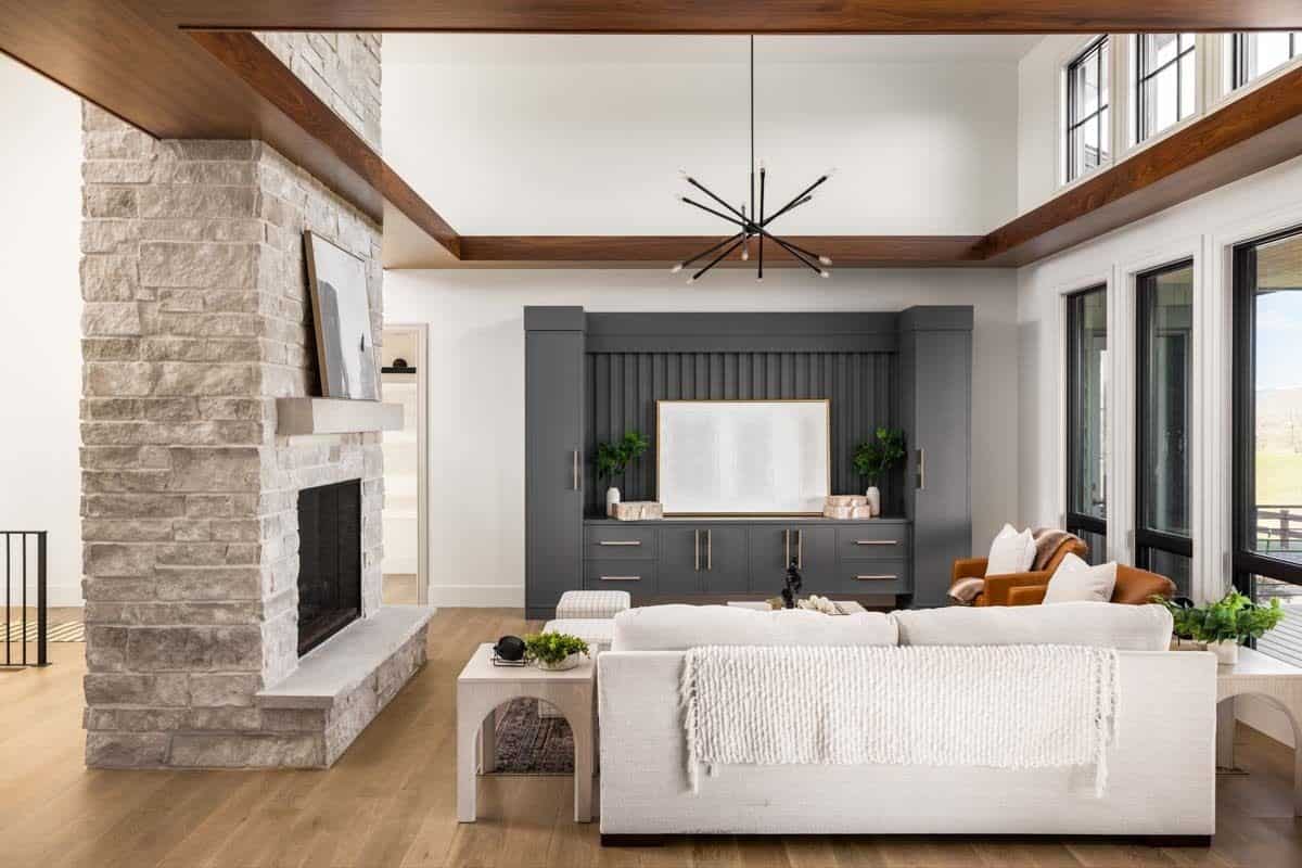 The great room includes a stone fireplace and a TV sitting on the gray cabinet.