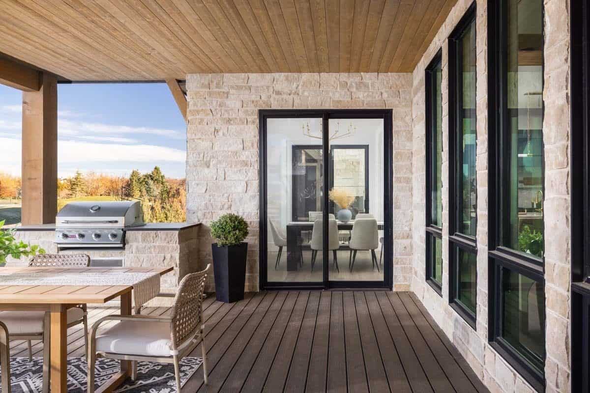 Covered patio with a summer kitchen, a wooden dining set, and a wood-paneled ceiling mirrored on the wide plank flooring.