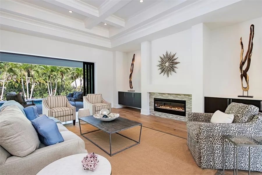 Great room with mismatched seats and a linear chandelier adorned with a sunburst mirror.