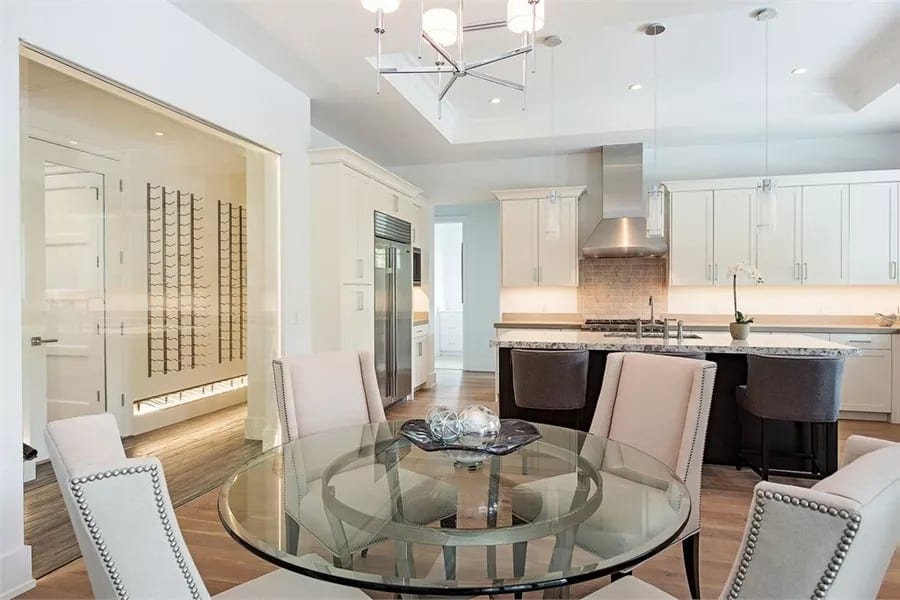 Breakfast nook with a round glass-top table surrounded by wingback chairs.