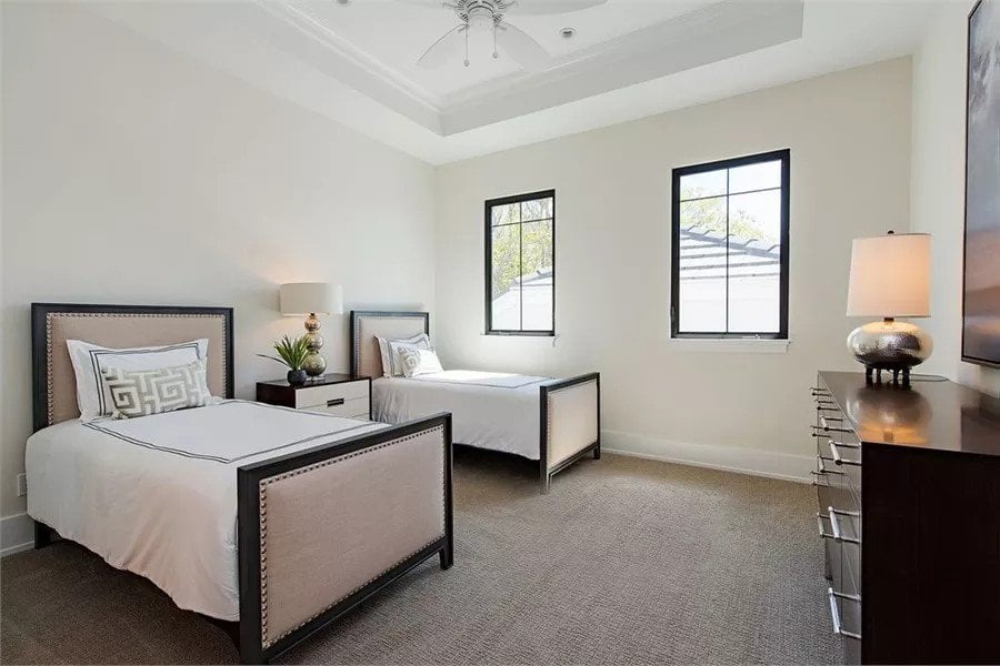 Bedroom with two beds and a dark wood dresser under a tray ceiling.