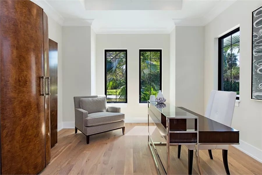 Home office with built-in cabinets, upholstered chairs, and a contemporary desk over the hardwood flooring.