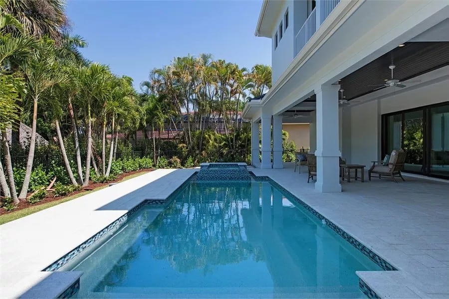 Swimming pool with a hot tub bordered by tiled paving.