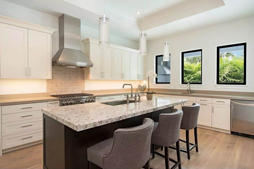 Kitchen with cream cabinets, a center island, and a trio of windows allowing natural light in.