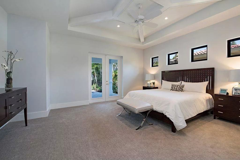Primary bedroom with dark wood furnishings and lanai access via a French door.