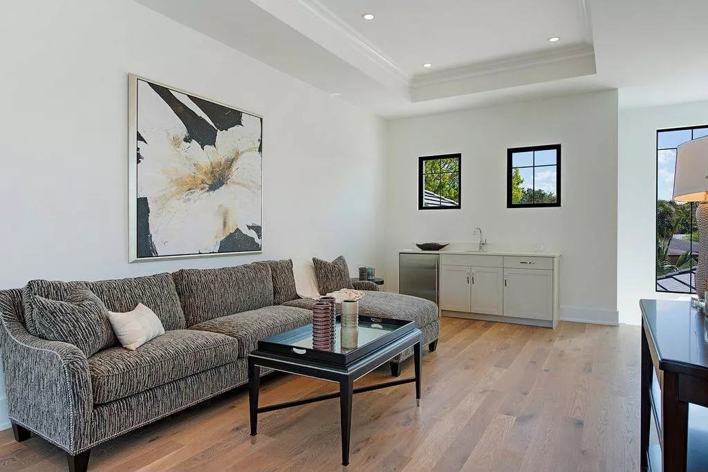 Study area with a tray ceiling, a sectional sofa, and a wet bar.