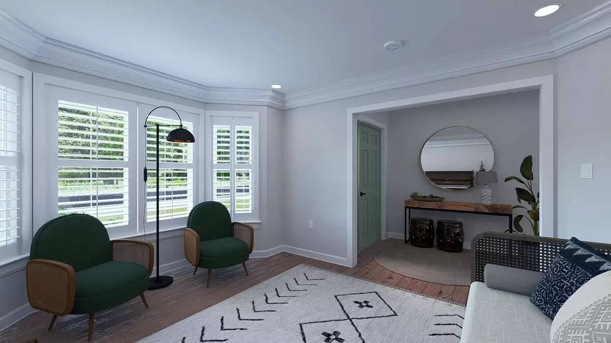 Living room with a wicker sofa and round back chairs against the bay window.