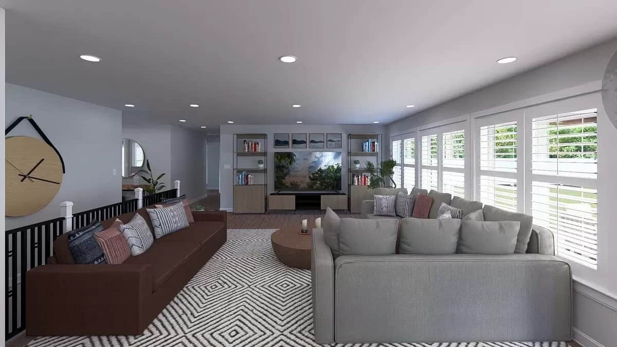 Family room with gray and brown sofas, a wall-mounted TV, and louvered windows flooding the area with ample natural light.