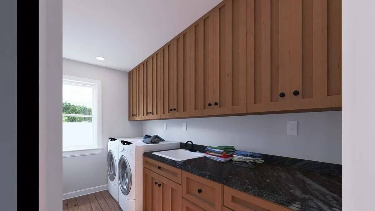 Laundry room with wooden cabinets, marble countertops, and a utility sink.