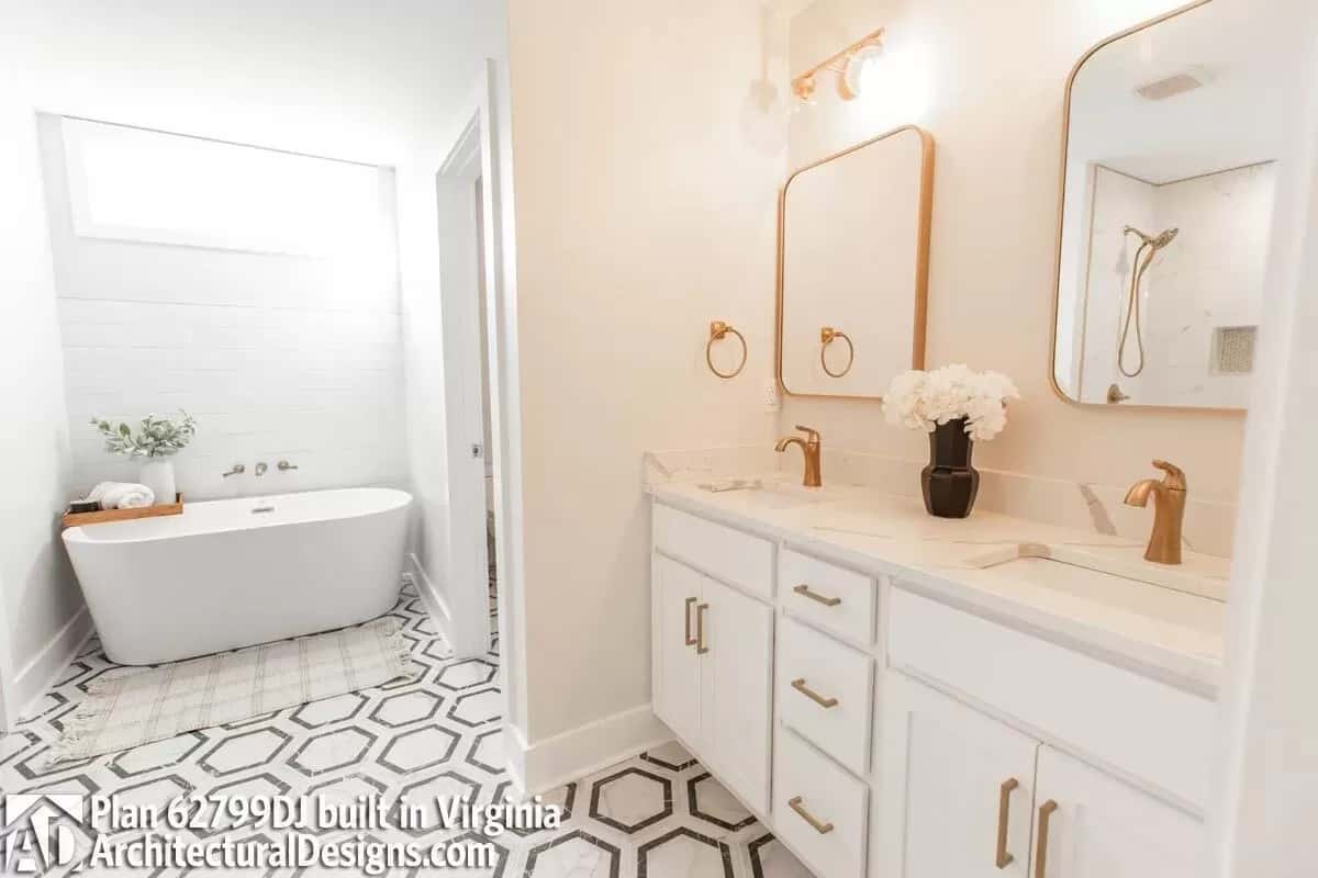 Primary bathroom with a soaking tub and a floating vanity with two sinks and brass-framed mirrors.