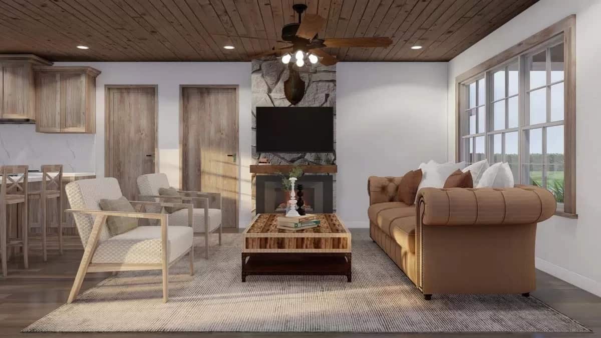 Great room with a chesterfield sofa, cushioned chairs, and a stone fireplace with a TV on top.