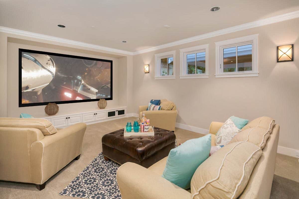 Media room with beige seats, a tufted ottoman, and a large projector screen.