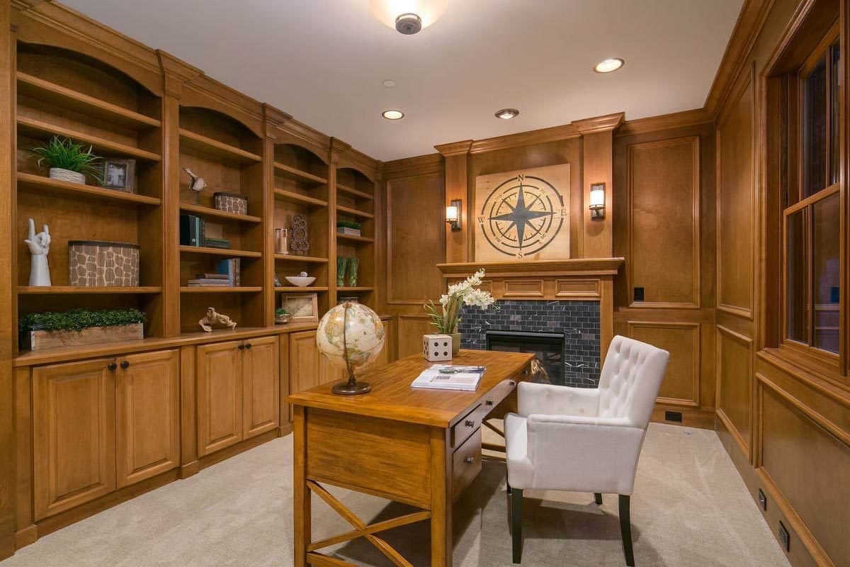 Office with a fireplace, wooden built-ins, and a matching desk paired with a tufted chair.