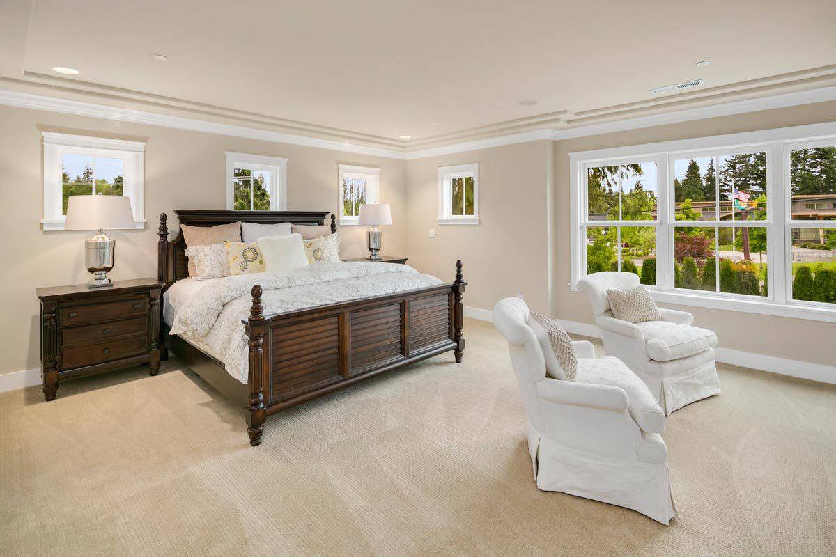 Primary bedroom with skirted chairs and a dark wood bed flanked by matching nightstands.