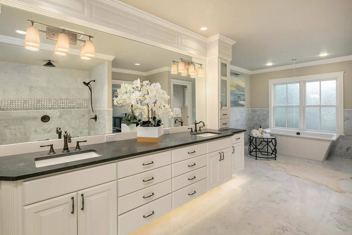 Primary bathroom with a dual sink vanity and a soaking tub brightened by white-framed windows.