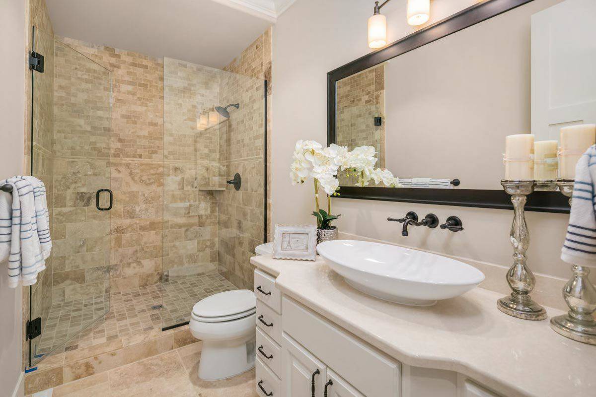 Bathroom with a walk-in shower and a white vanity topped with a vessel sink and rectangular mirror.