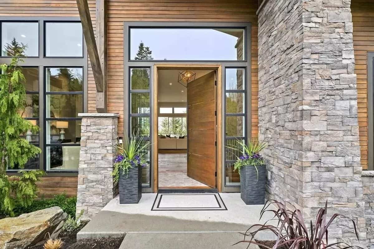 Front entry with a wooden front door surrounded by sidelights and a transom window.