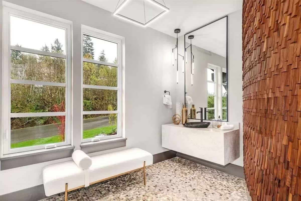 Powder room with a floating vanity and cushioned bench against the large windows.