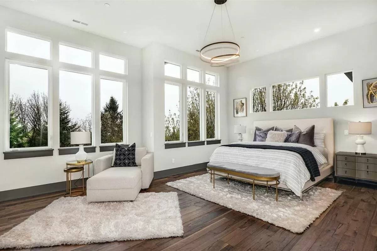 Primary bedroom with an upholstered bed and a chaise lounge over the the shaggy rugs.